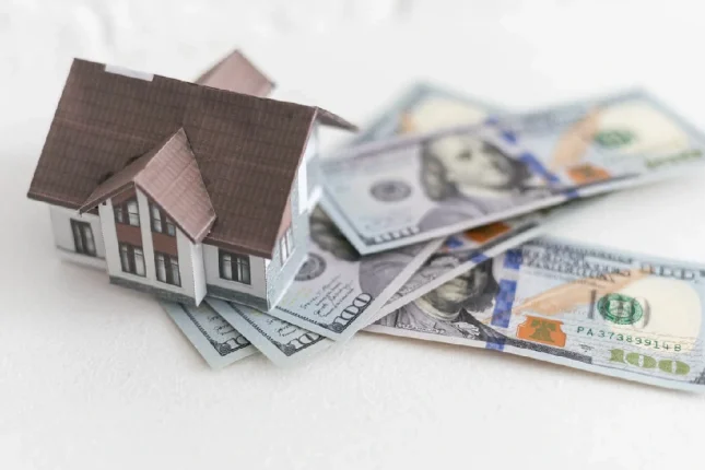 House standing on a pile of dollar bills investment